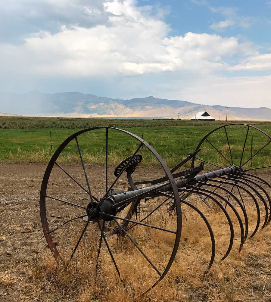 metal agricultural equipment with a grassy valley and mountain in the background