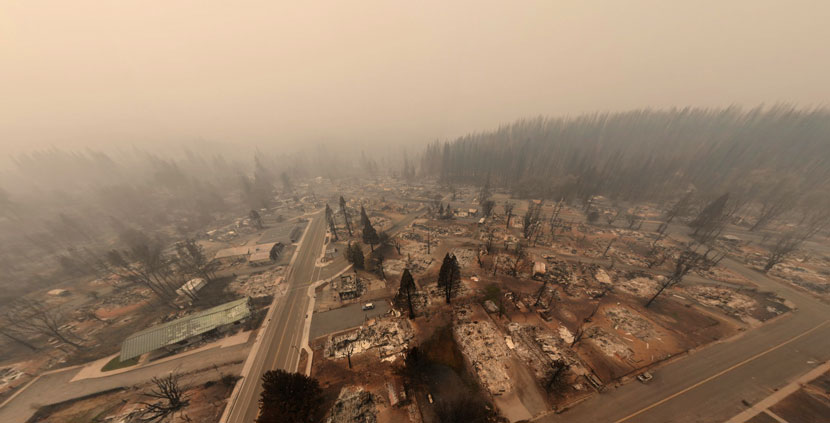 looking up and down at a smoky, scorched community with most structures non-existent