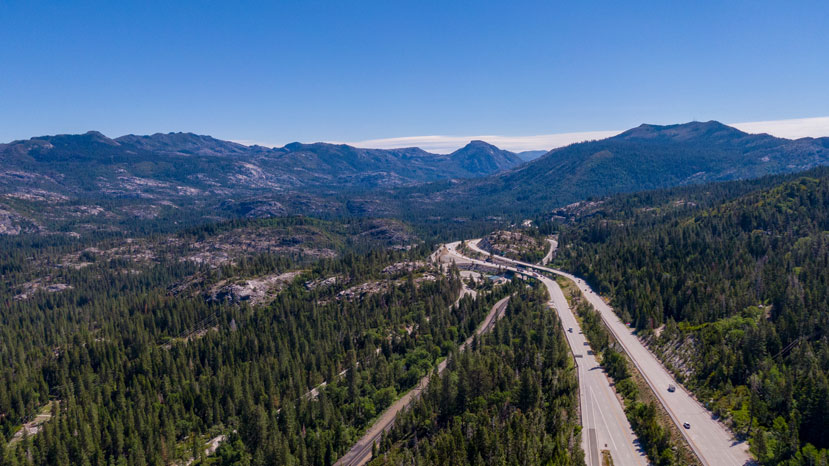 aerial view looking out along highway with forested mountains in the background - no snow is visible
