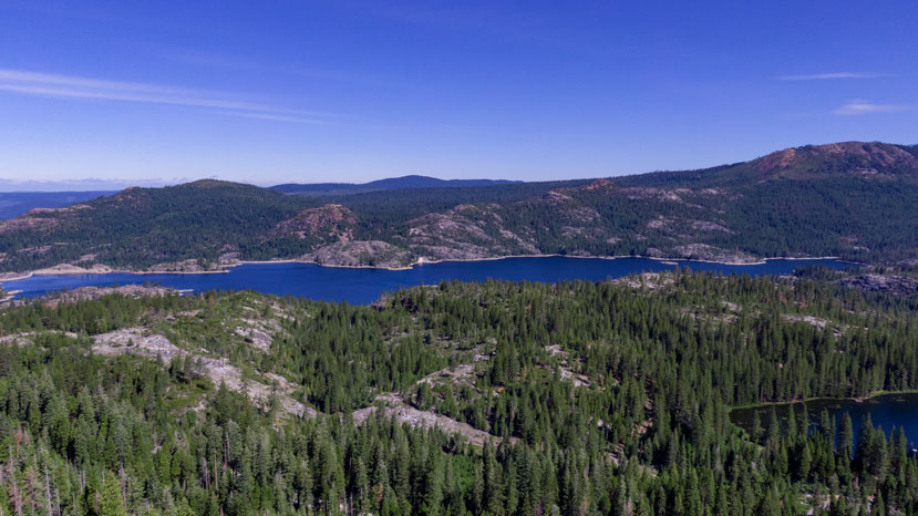 aerial image looking out across a lake with trees in the foreground and background - no snow is visible