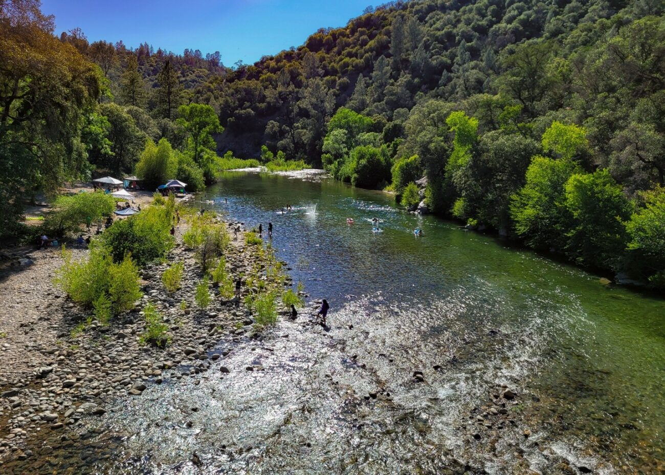 A river with trees and people alongside it.