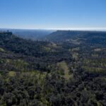 An aerial shot of green hills, trees and mesas.