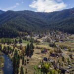 An aerial shot of a small town in the mountains next to a river.