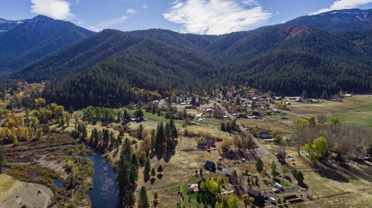 An aerial shot of a small town in the mountains next to a river.