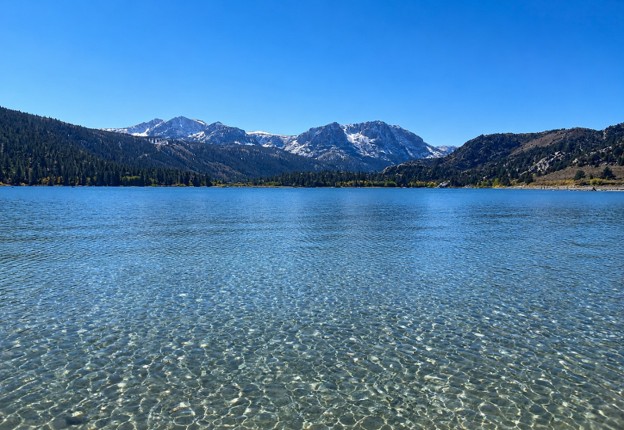 A lake with snow capped mountains in the background